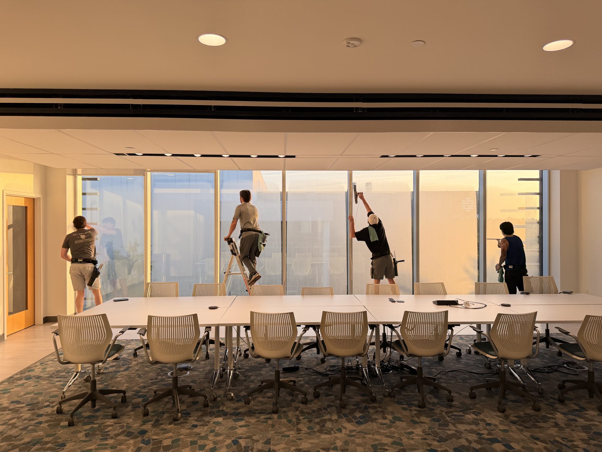 Interior commercial window cleaning: crew cleaning floor-to-ceiling glass in a conference room