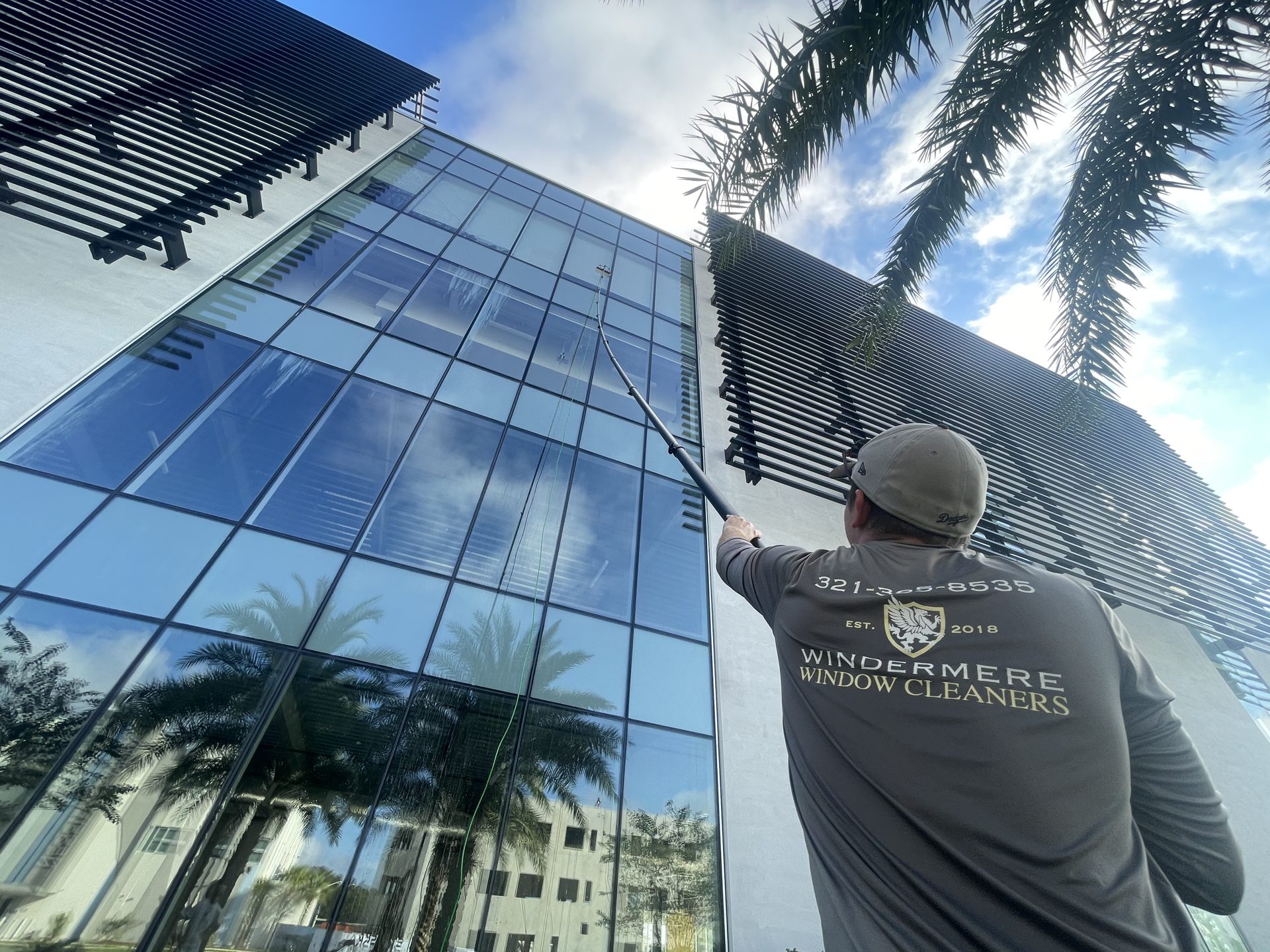 Commercial window cleaning in Central Florida: technician using a water-fed pole on a multi-story glass office building