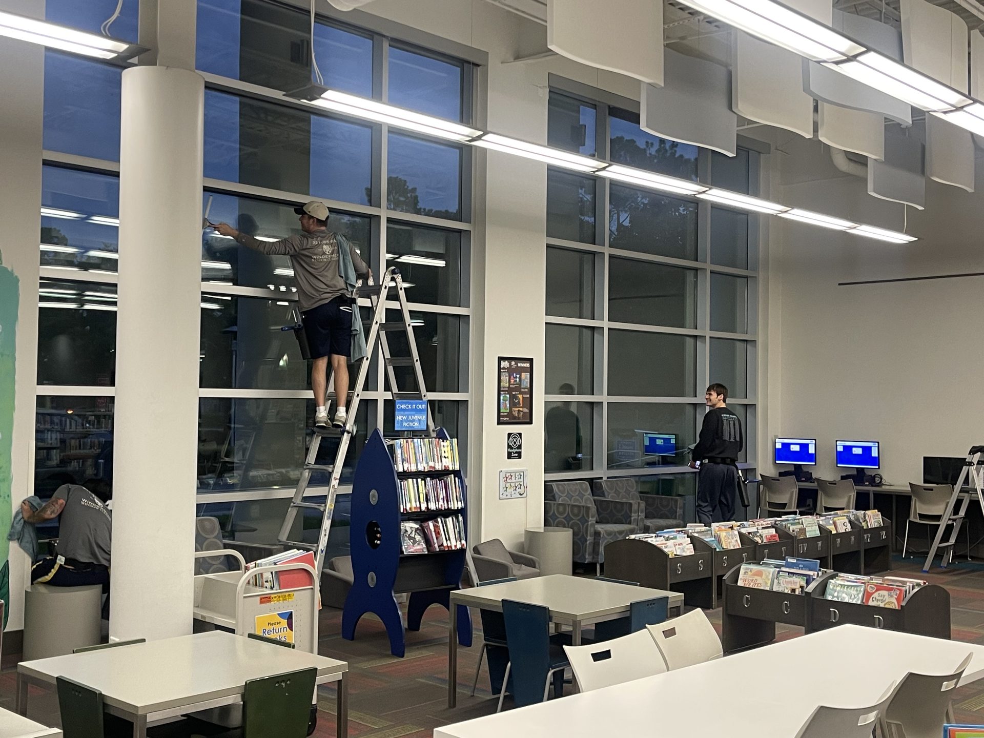 Interior window cleaning on a two-story glass wall in a library