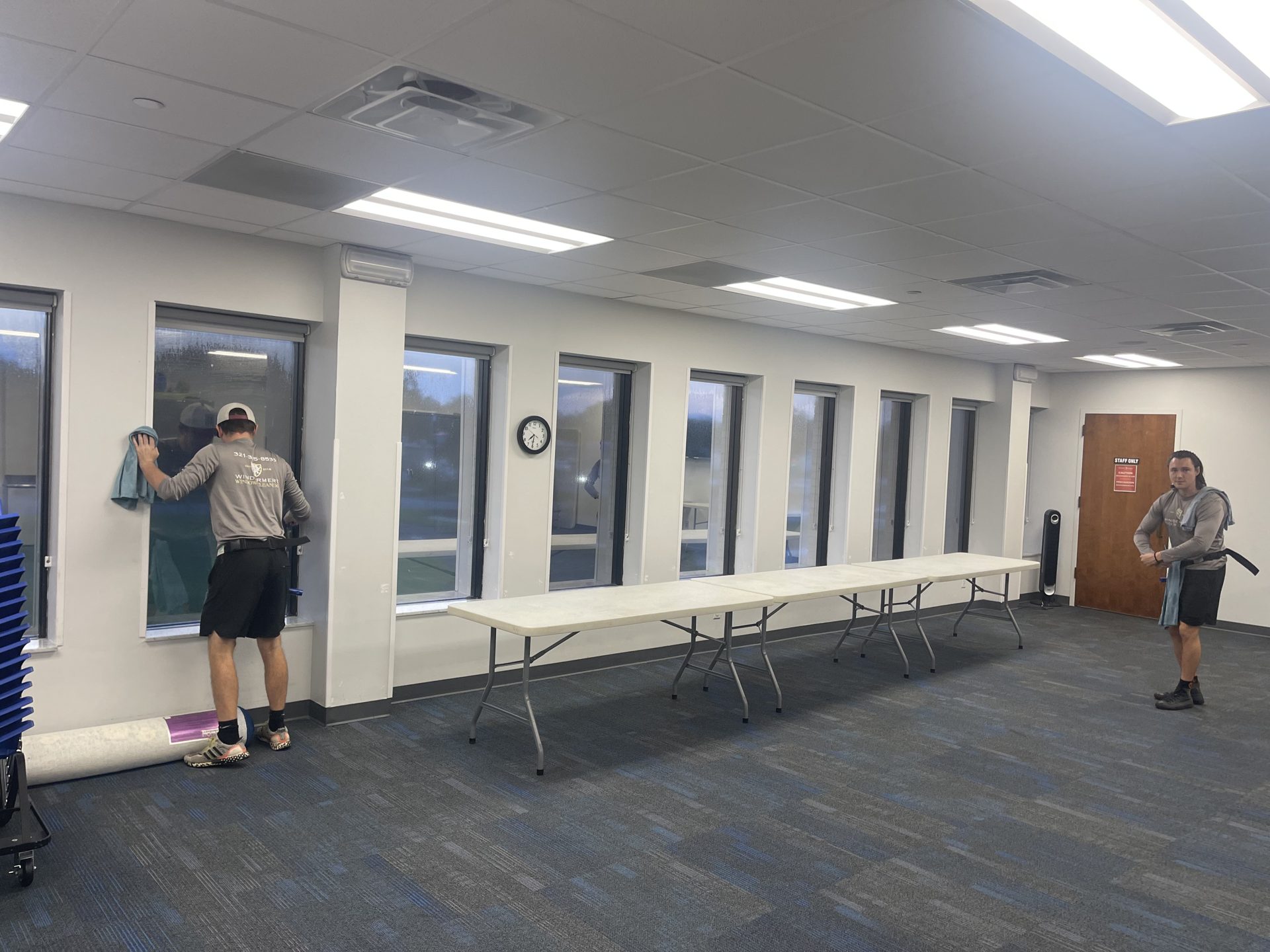 Technician cleaning the interior windows of a meeting room