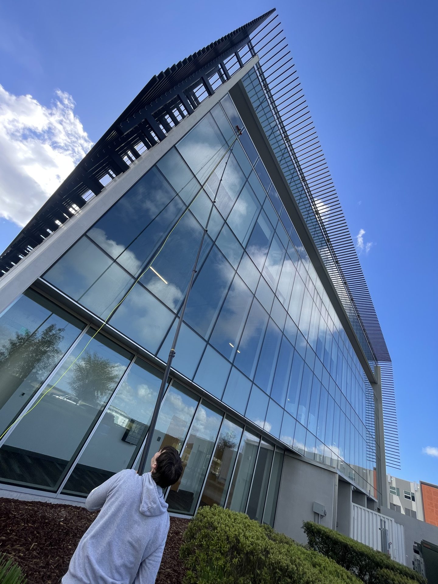Water-fed pole window cleaning on a modern glass office building