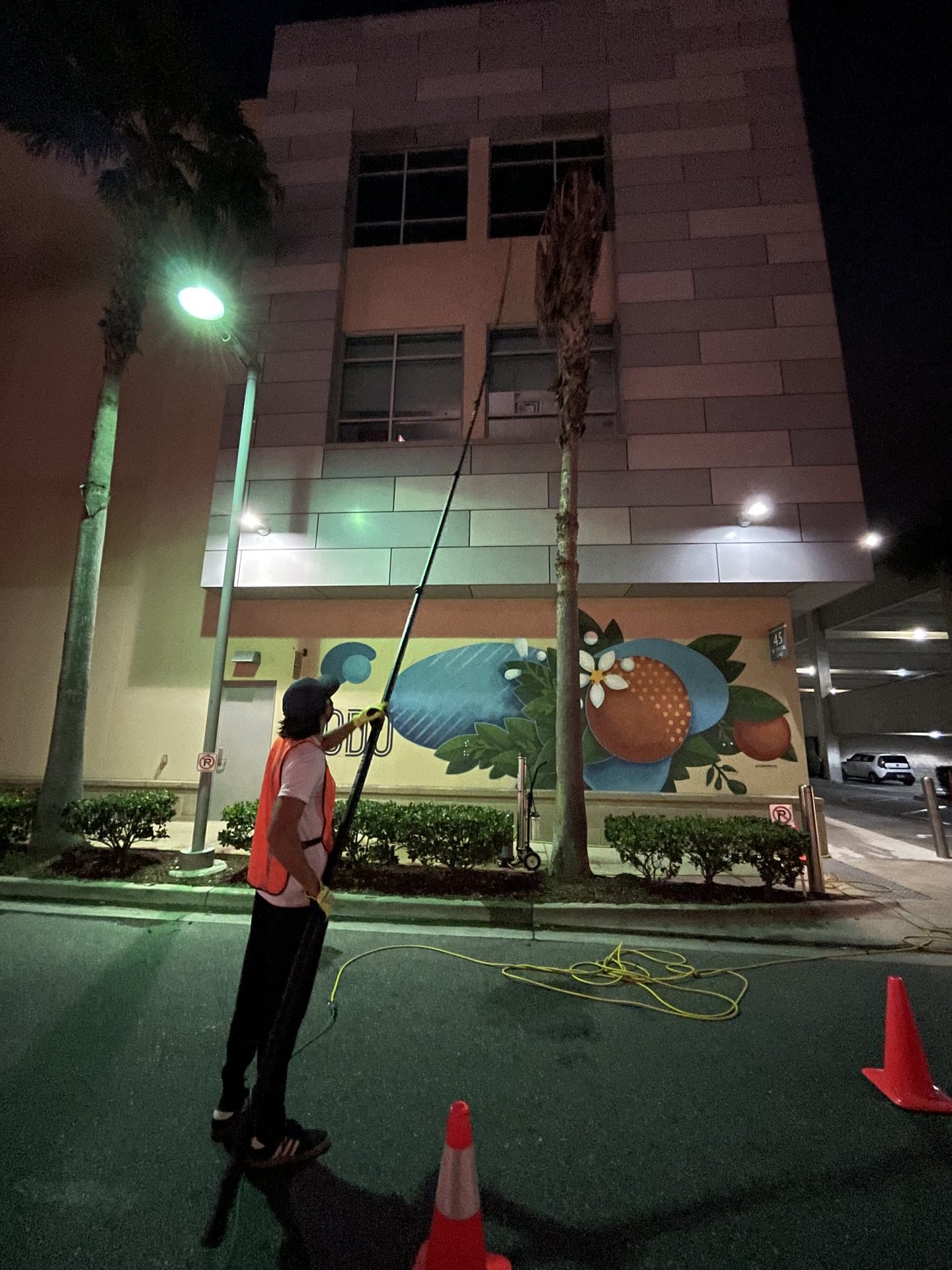 Technician cleaning storefront windows at night, working around business hours
