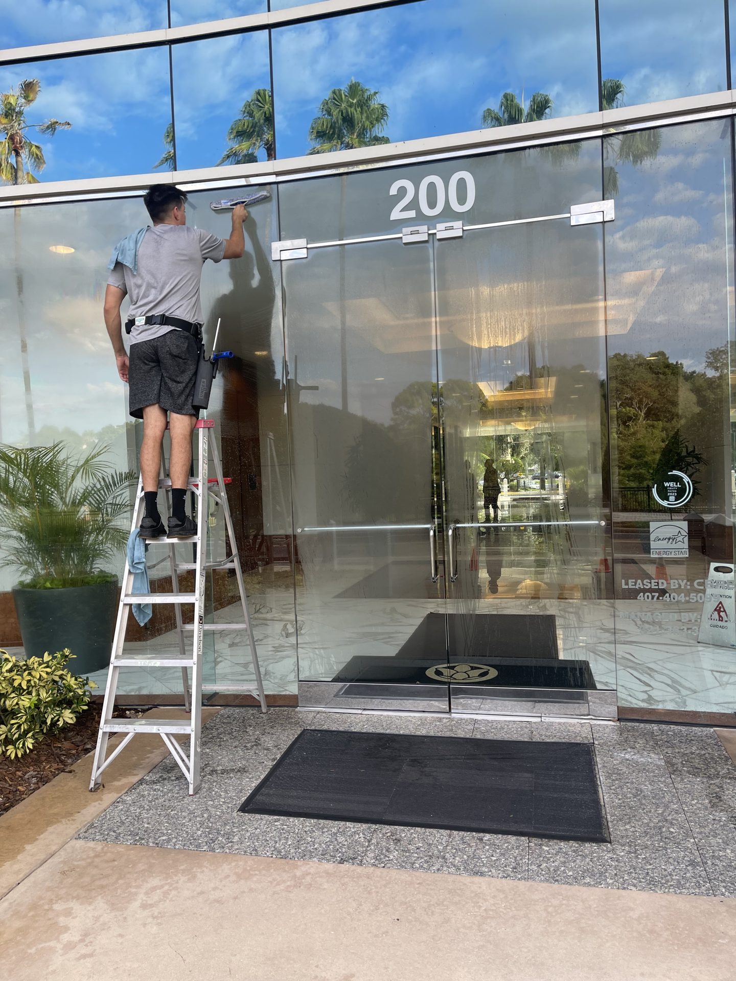 Technician cleaning the glass entrance of an office building