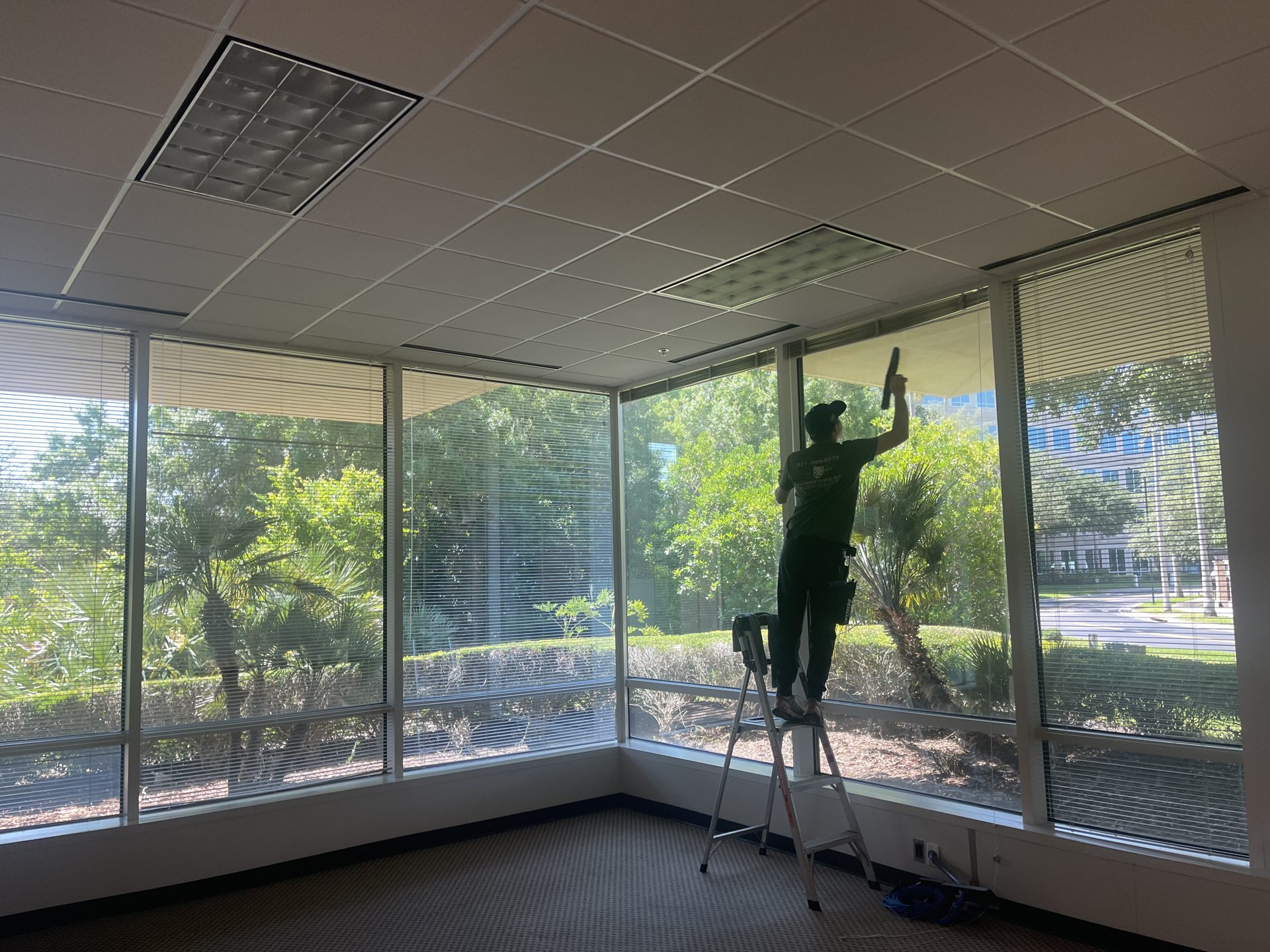 Technician cleaning the corner windows inside a professional office