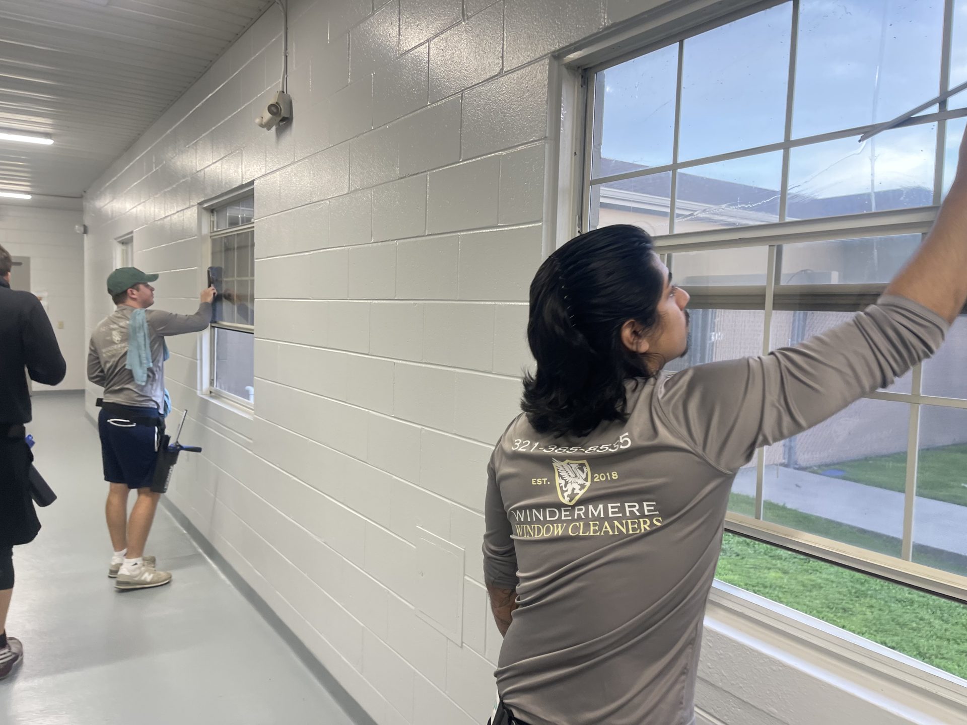 Technician cleaning the interior windows of a school corridor