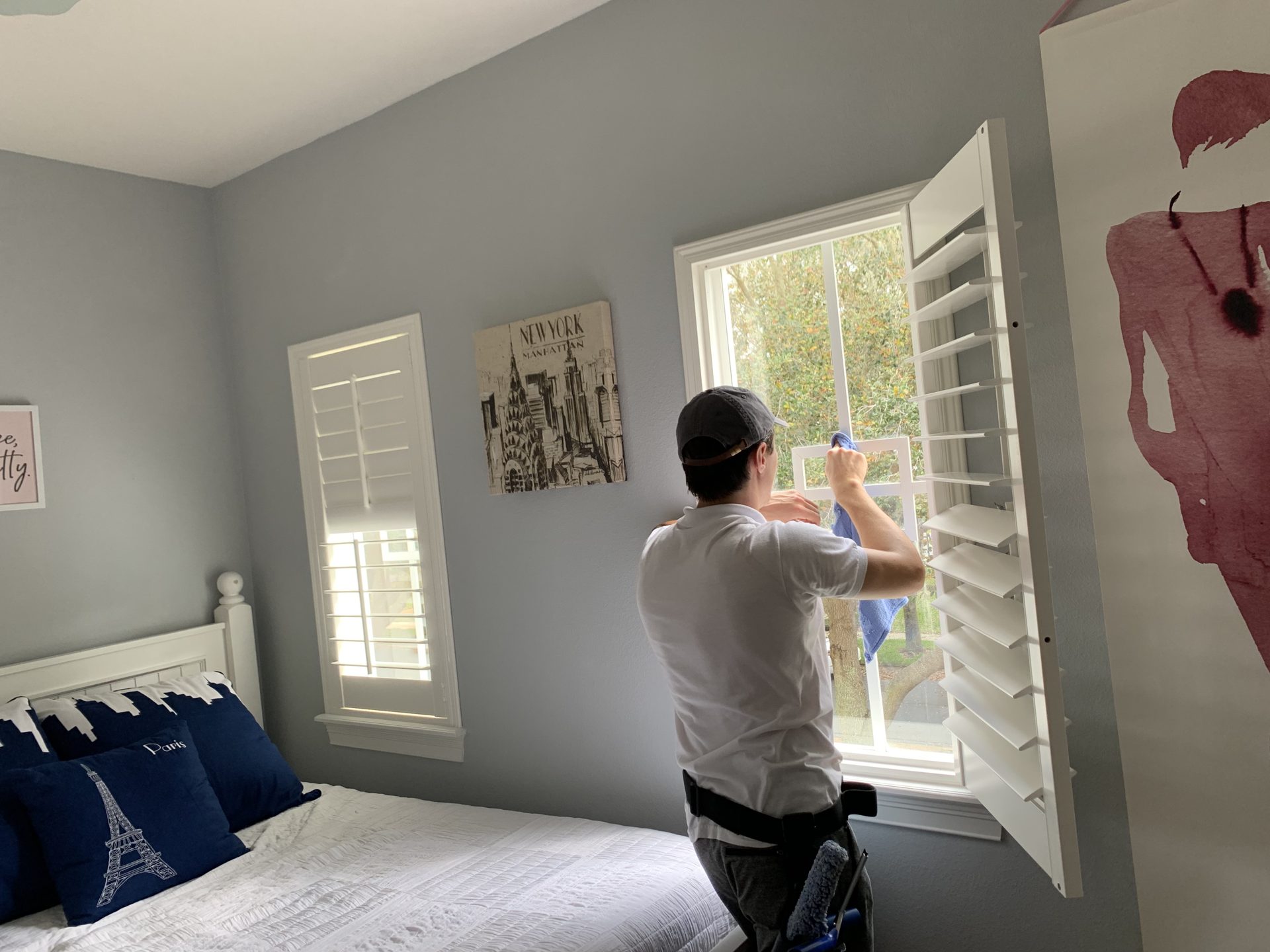 Interior window cleaning in a bedroom with plantation shutters