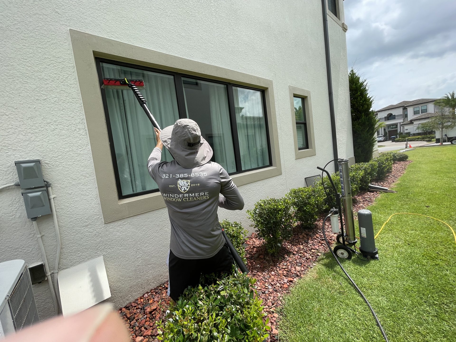 Technician hand-cleaning a ground-floor window of a home