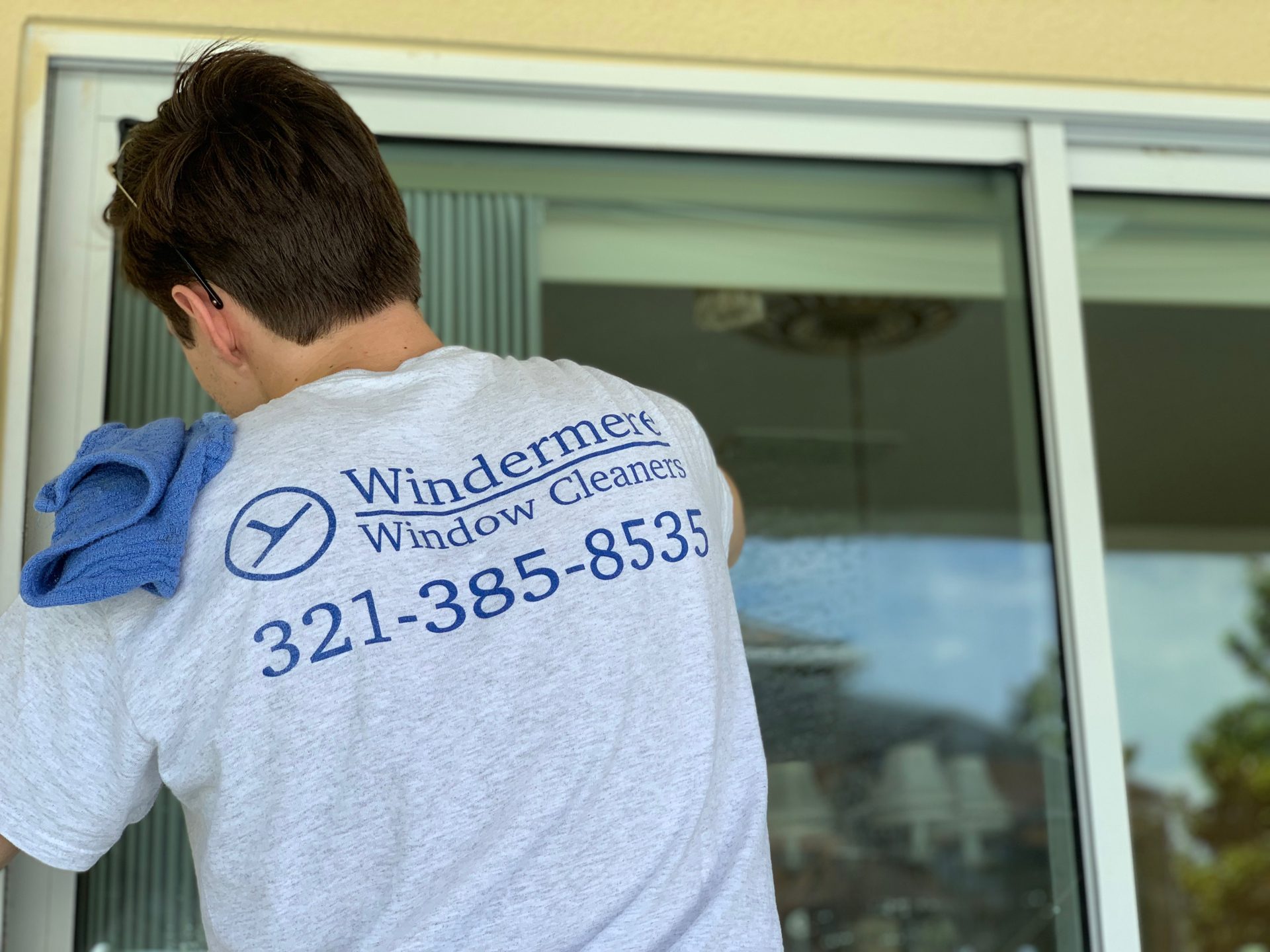 Windermere Window Cleaners technician cleaning a sliding glass door