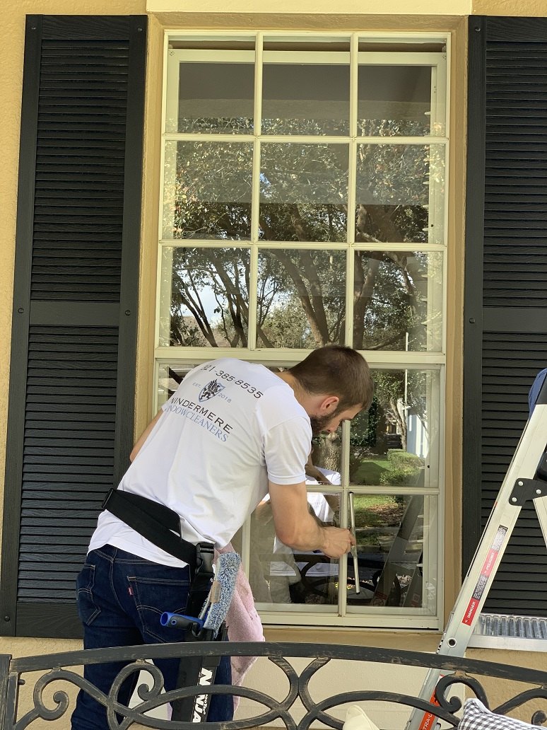 Technician hand-cleaning a home's French windows